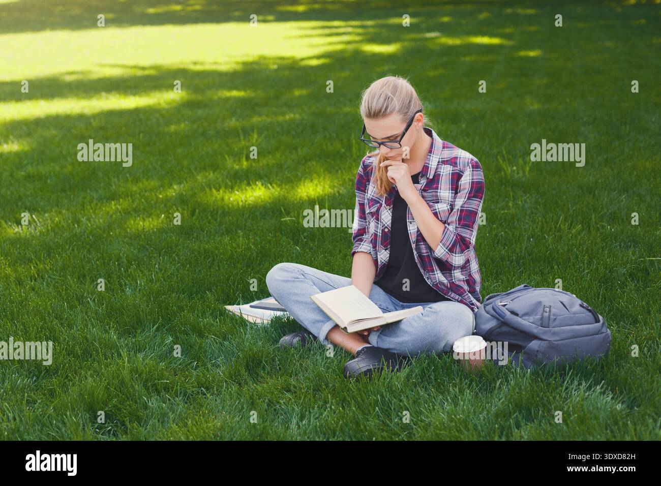Libro di lettura sull'erba nel parco durante la giornata di sole Foto Stock