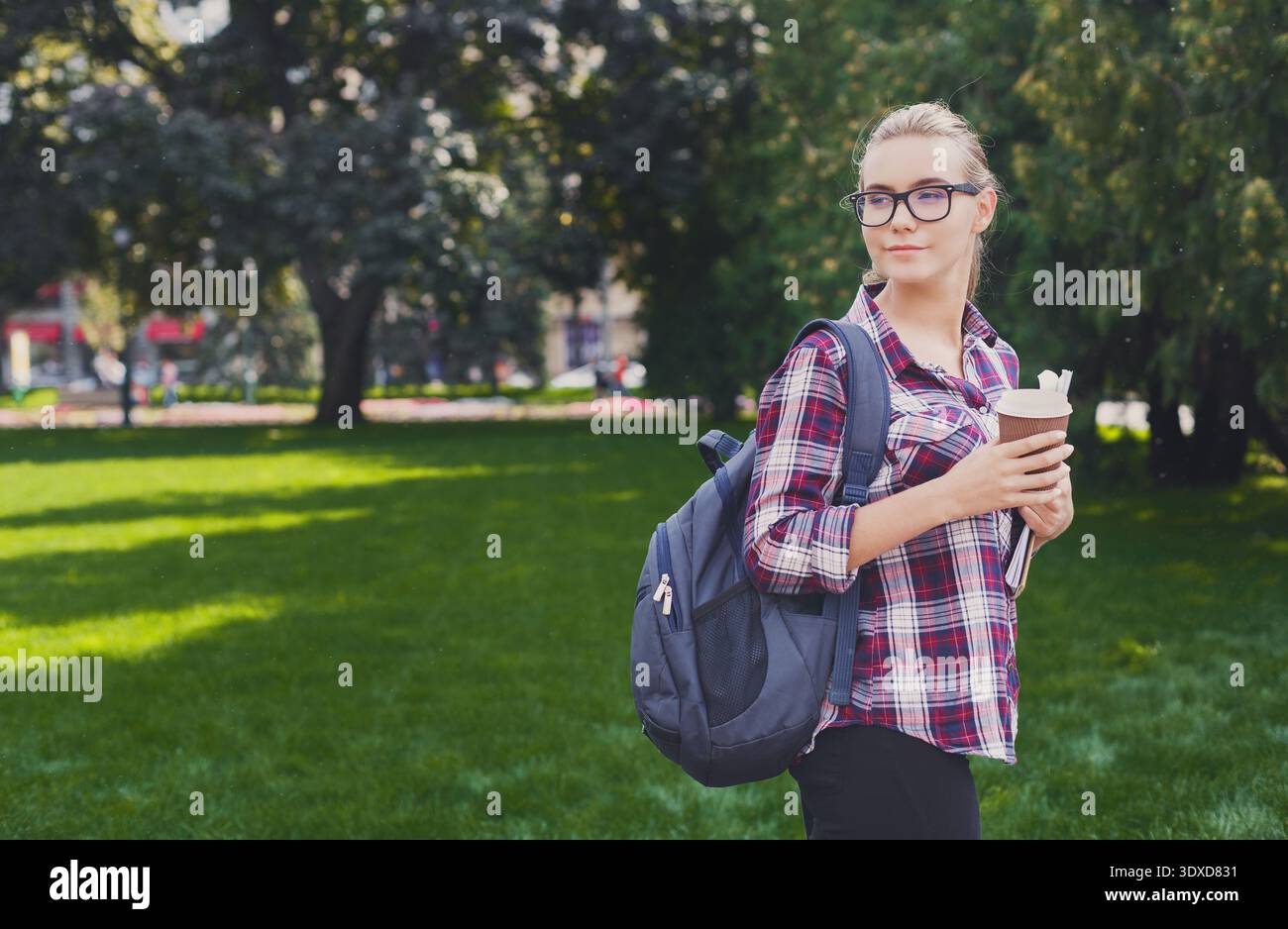 Un giovane adulto si trova in un parco con erba verde Foto Stock