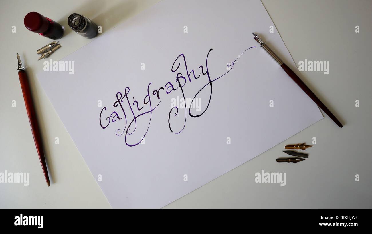 Parola scritta per calligrafia su carta bianca scritta con penna a immersione e inchiostro viola. Scrittura artistica a mano con pennini e bottiglie d'inchiostro per creatività Foto Stock