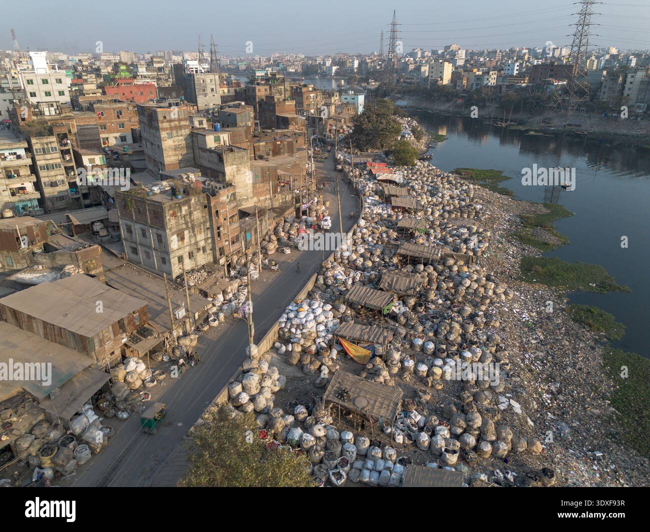 Vista aerea di montagne di rifiuti plastici in contrasto con il paesaggio urbano, che costeggiano il fiume Buriganga, Dacca, Divisione di Dacca, Bangladesh. Foto Stock