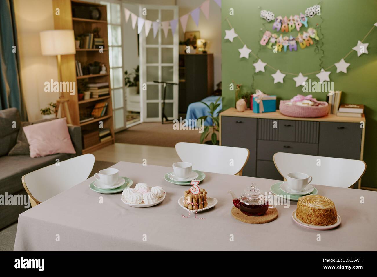 Tavolo di compleanno con torta e dolci nel soggiorno decorato Foto Stock