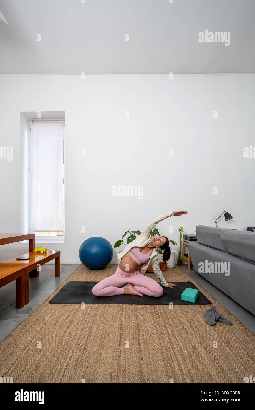 Donna incinta che pratica yoga prenatale Stretch all'interno Foto Stock