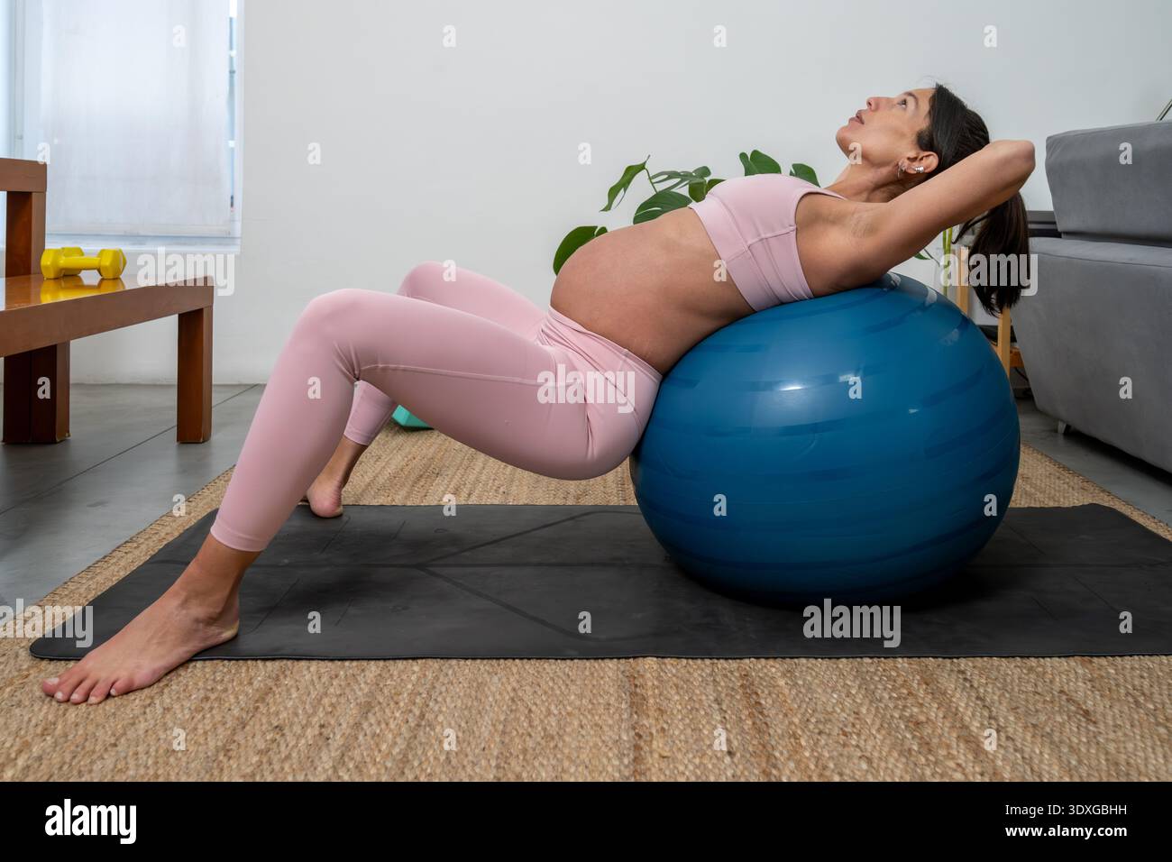 Donna incinta che svolge esercizio di palla di stabilità a HomePregnant Woman Training con palla di esercizio al chiuso Foto Stock