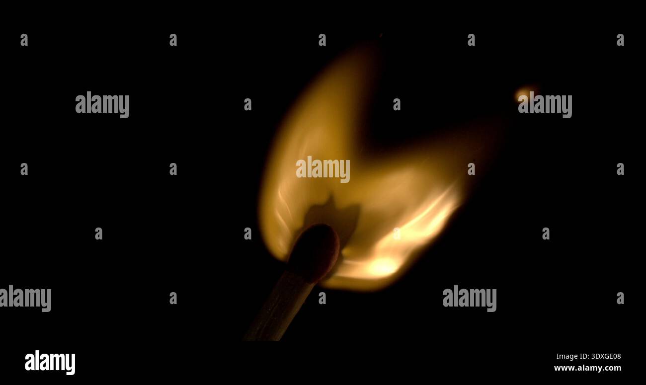 Fiamma da una fiamma illuminata al buio con fumo che arriccia sopra e una luce brillante che splende sotto Foto Stock