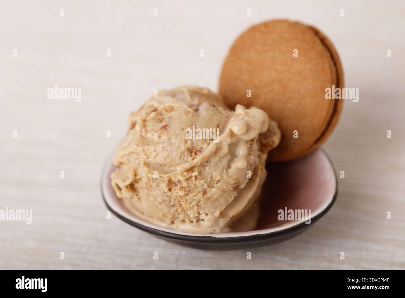 Una paletta di gelato cremoso al caramello condita con un biscotto al caramello, servito in una piccola ciotola Foto Stock