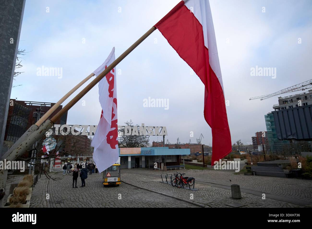 bandiera nazionale polacca e bandiera di solidarietà che battono contro il cielo grigio al di fuori del cantiere navale di danzica in polonia Foto Stock