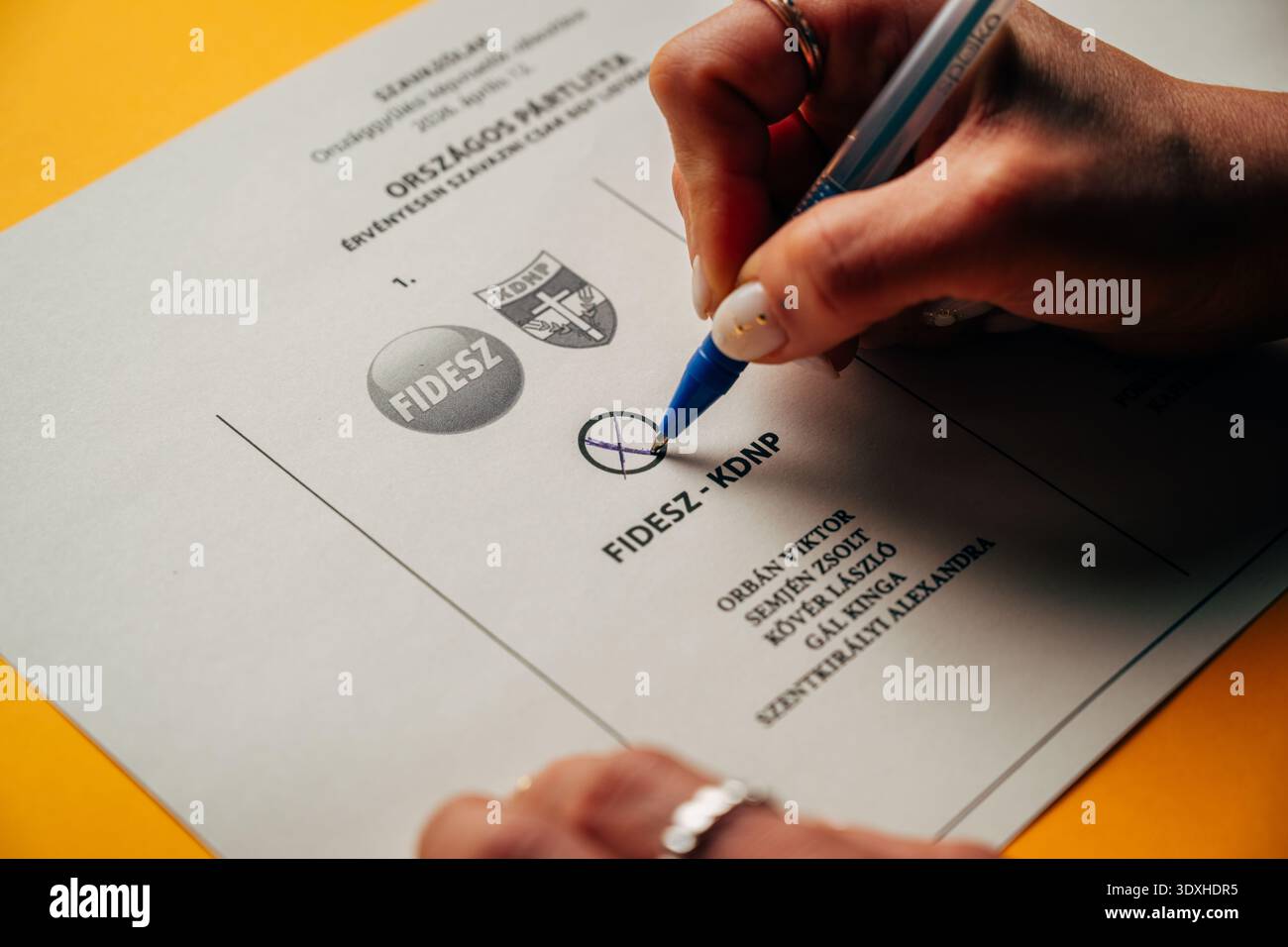 La mano di una donna che segna una carta elettorale con una penna, che vota per il partito Fidesz-KDNP Foto Stock