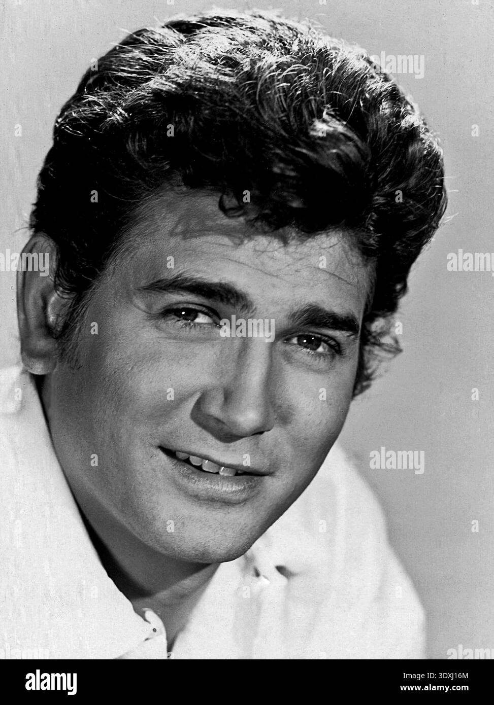 Un headshot pubblicitario in bianco e nero dell'attore americano Michael Landon degli anni '1960, che cattura il suo aspetto giovanile. Viene mostrato con un sorriso casuale, guardando direttamente la telecamera, con un'evidenziazione luminosa sui suoi capelli scuri e ondulati. Foto Stock