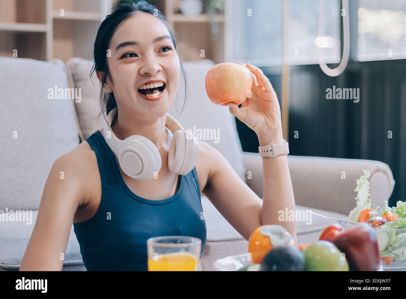 Indossare giovani donne asiatiche in abbigliamento sportivo sedute su un tappetino da yoga e mangiate insalata di verdure fresche dopo l'allenamento, che rappresentano un'alimentazione pulita, uno stile di vita fitness, Foto Stock