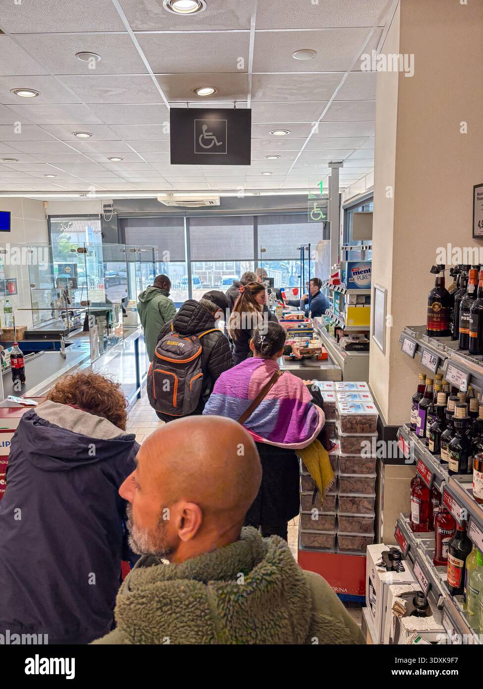 Lunga fila in una fila al supermercato Montpellier, in Francia. I clienti attendono il loro turno vicino a scaffali riforniti. Simbolo di accessibilità visibile. Foto Stock