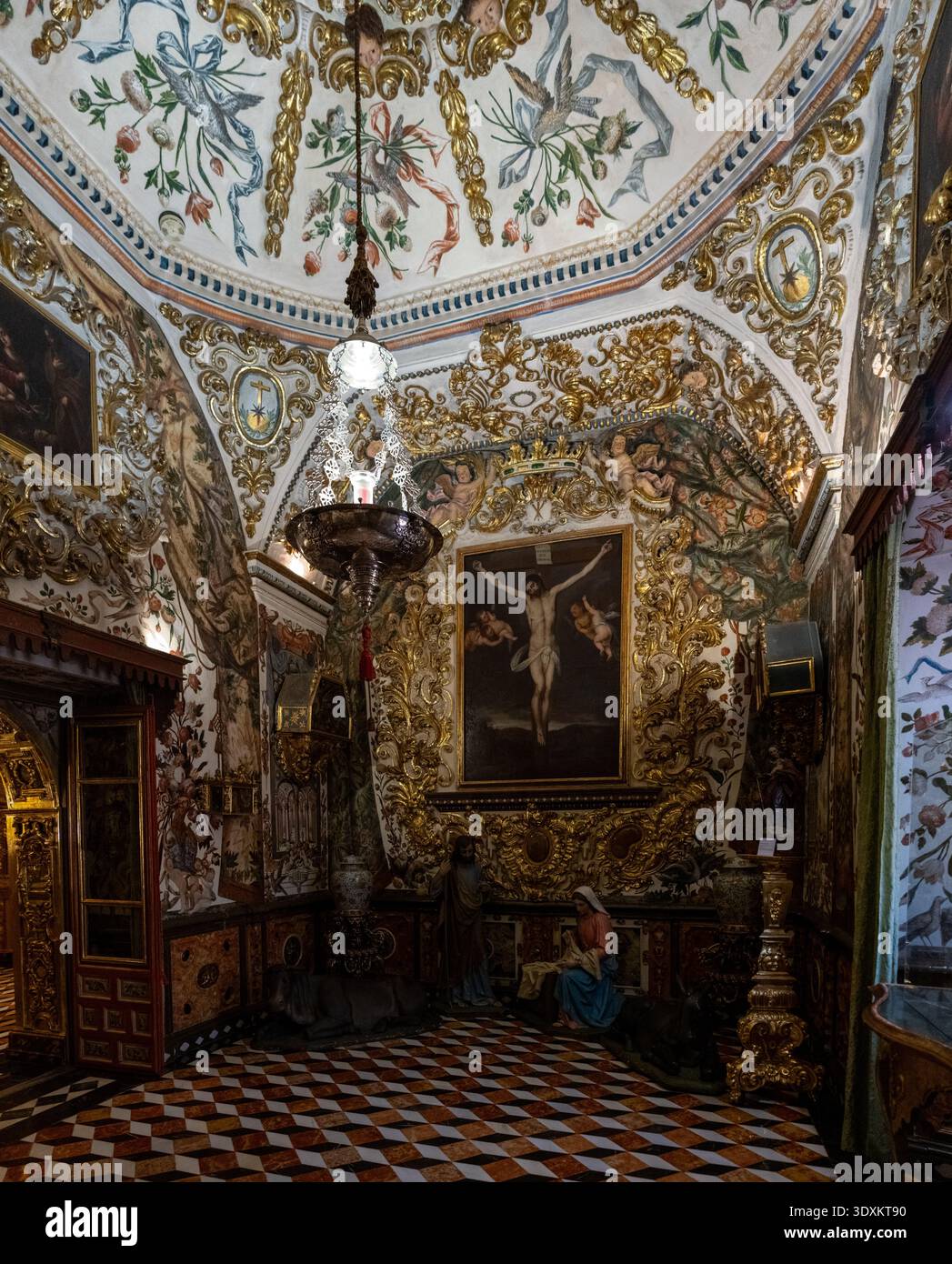 Grenada, Spagna - 19 dicembre 23: Cappella laterale decorata con stucco dorato, affreschi sul soffitto, lampadario e pavimento in marmo all'interno della Basilica de San Juan de Dio Foto Stock