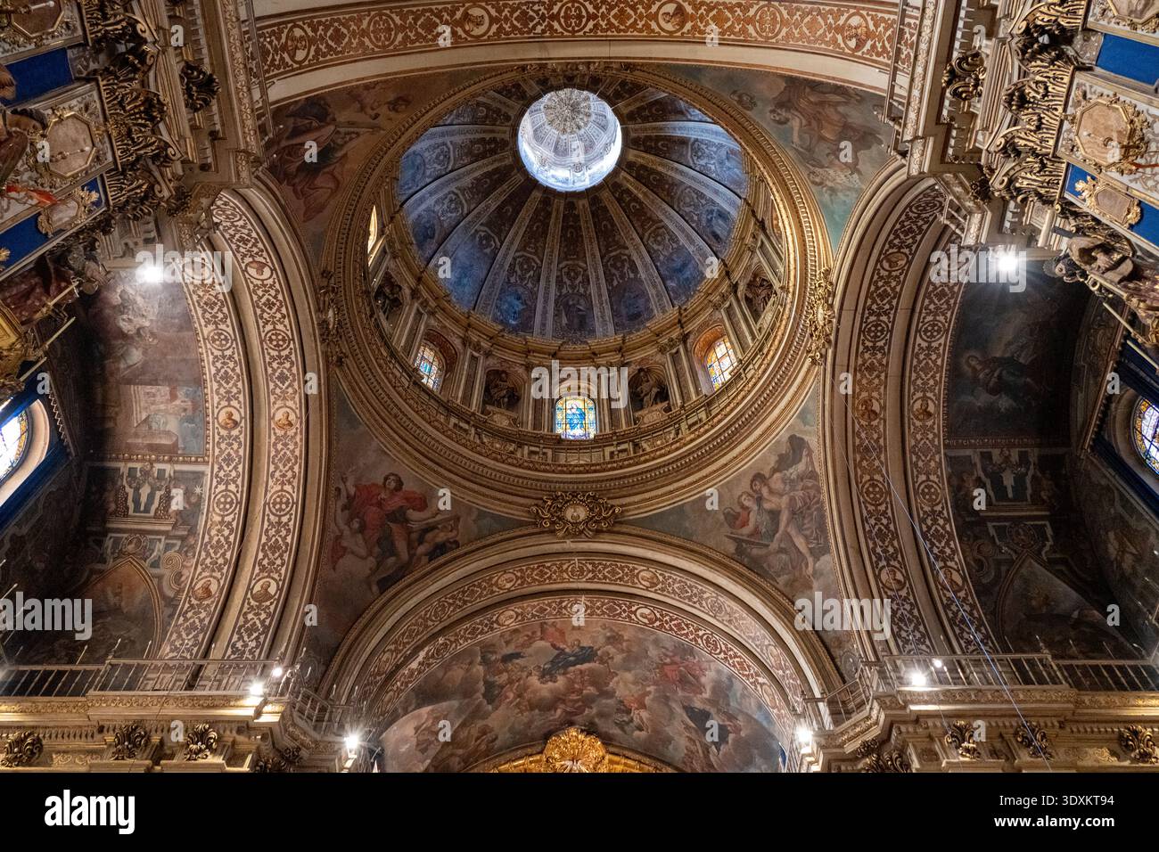 Vista interna verso l'alto di archi, affreschi e cupola centrale con vetrate colorate nella Basilica de San Juan de Dios, Granada, Andalusia, Spagna. Foto Stock