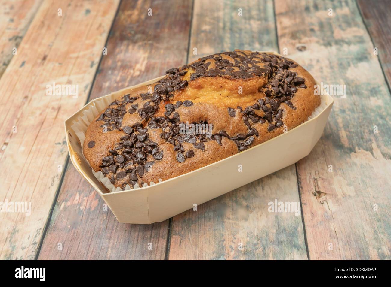 una torta di spugne al cioccolato riempita con una crema di cioccolato al latte liscia e ricoperta da una ganache a specchio color rosso rubino che riflette lo spettacolo leggero Foto Stock