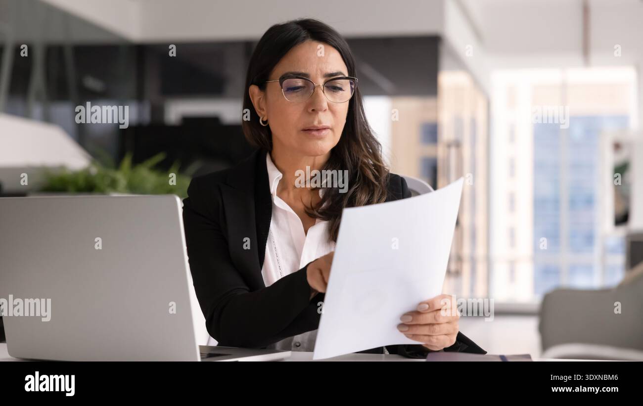 Donna professionista anziana che analizza documenti in ufficio Foto Stock