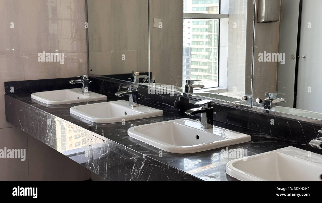 Bagno moderno con eleganti ripiani in marmo nero e lavandini bianchi. Foto di alta qualità Foto Stock