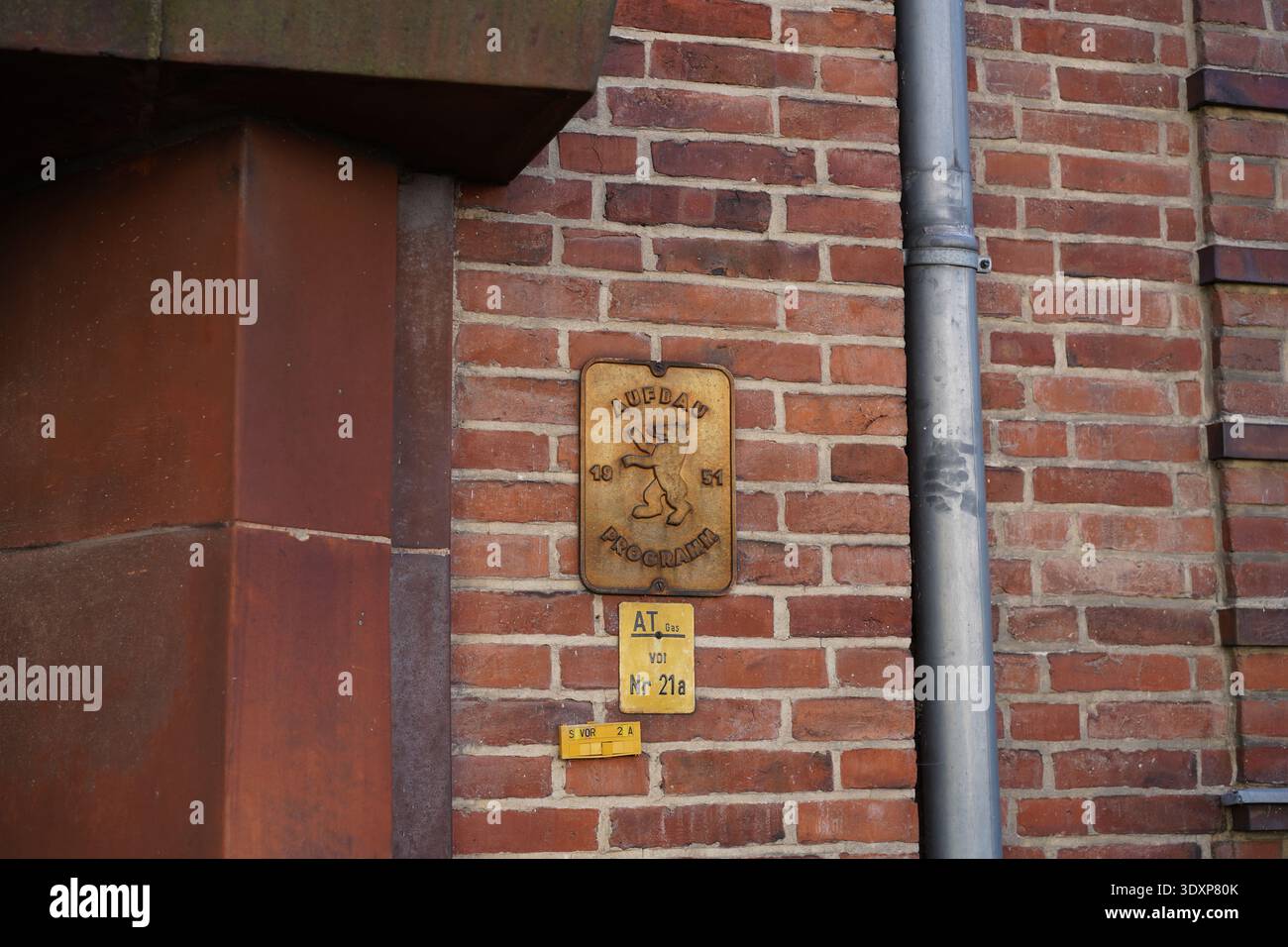 Berlino, Germania - 28 febbraio 2026: Una targa di bronzo del programma di ricostruzione di Berlino (1951) su un muro di mattoni a Lichterfelde. Foto Stock