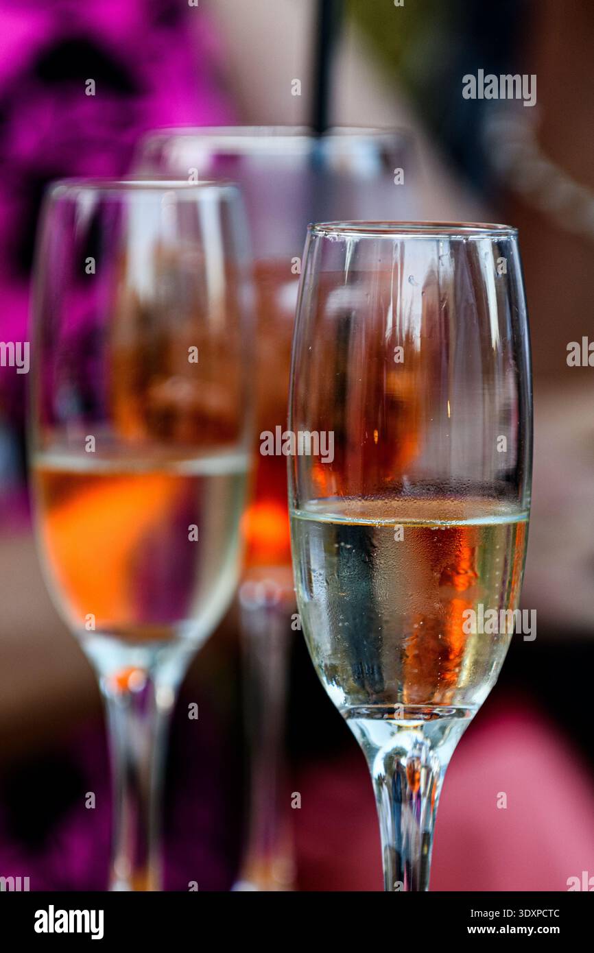 Due bicchieri di flauto in cristallo parzialmente riempiti con vino bianco seduti in un bar per un banchetto di nozze. Foto Stock