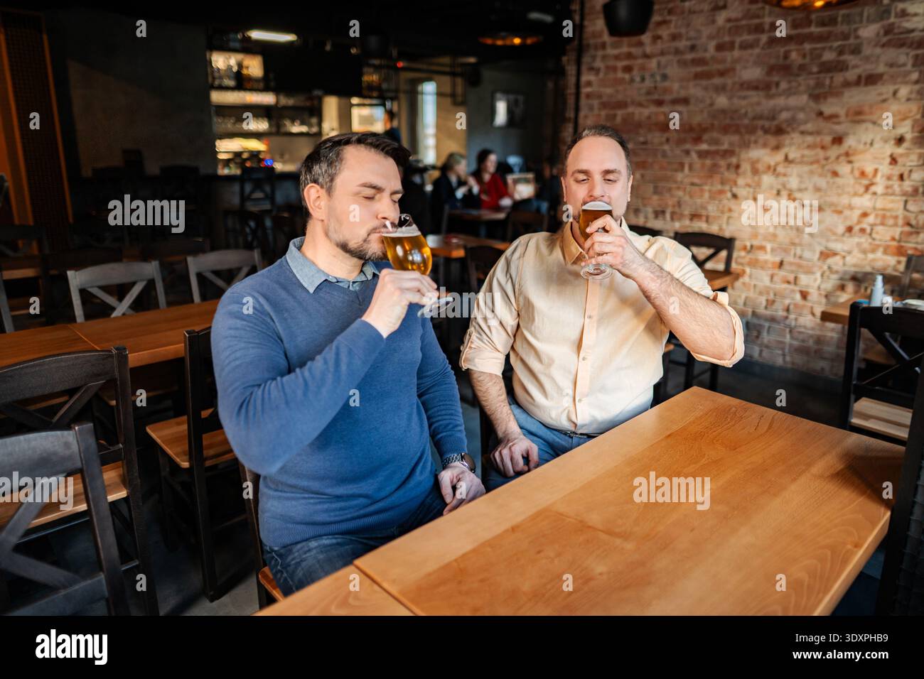 Due uomini si godono una degustazione di birra presso un birrificio locale Foto Stock