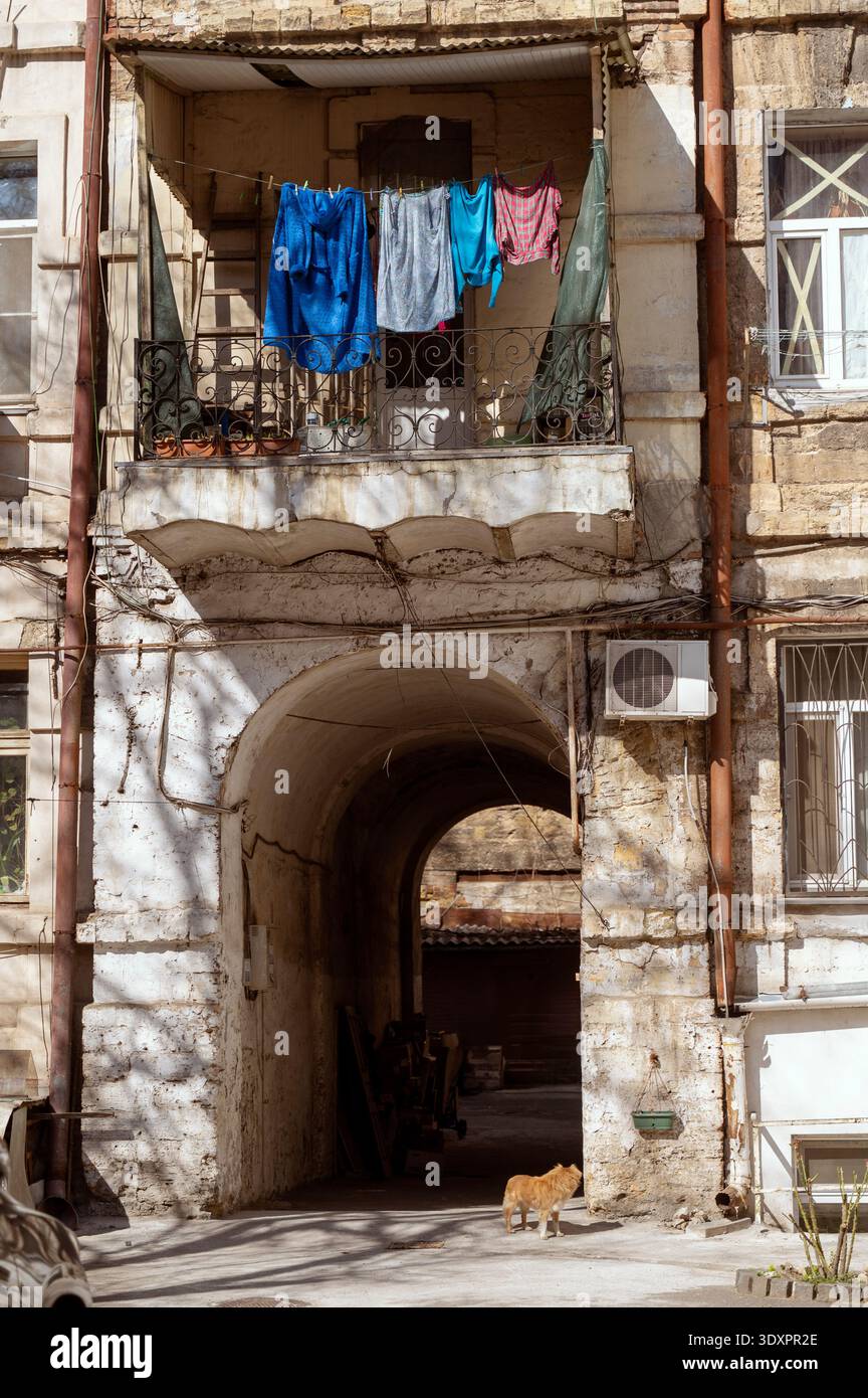 Vecchio edificio di appartamenti con ingresso ad arco e lavanderia colorata su un balcone. Foto Stock