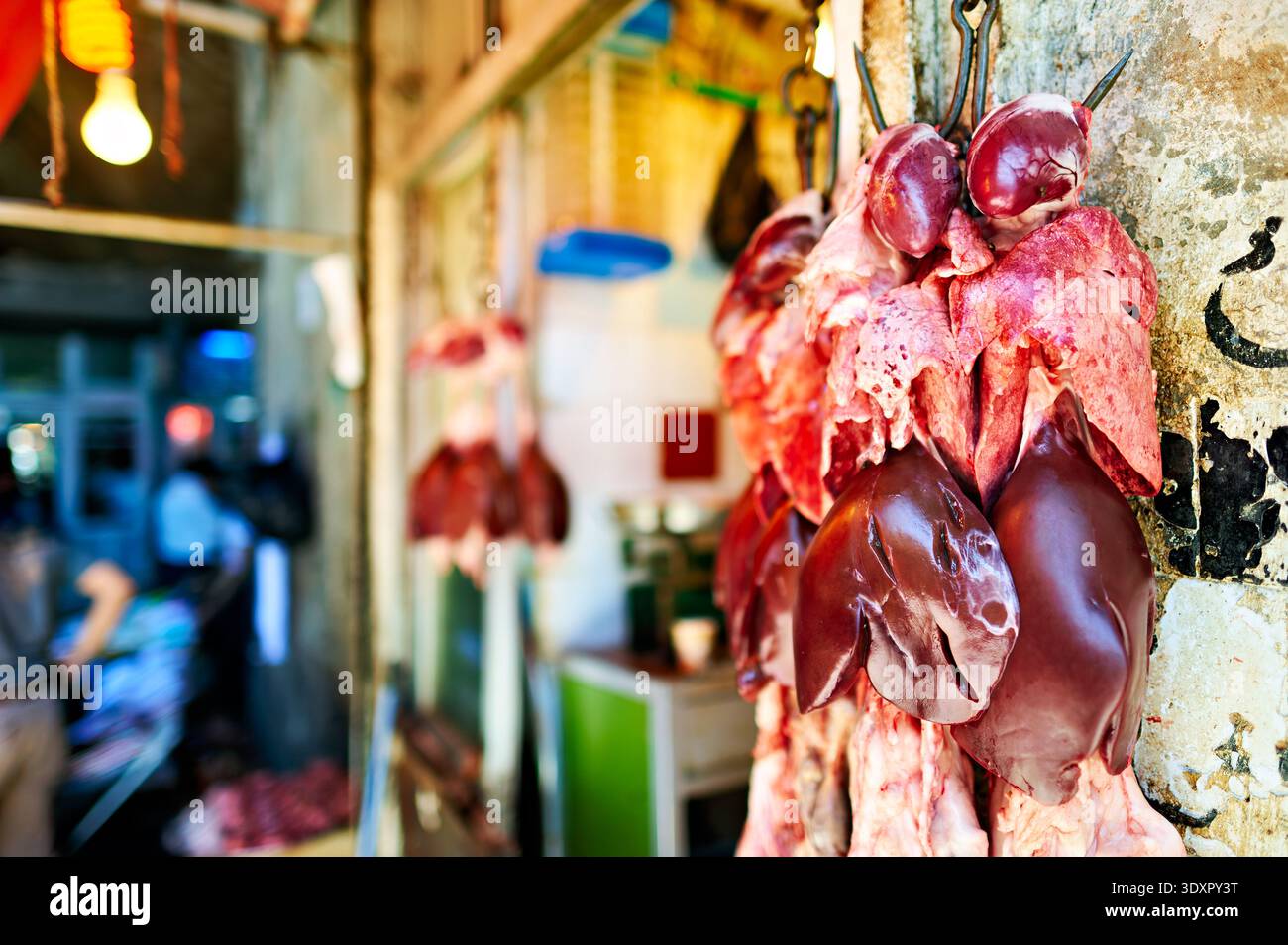 Un macellaio espone vari tagli di carne in un souq situato ad Aleppo, in Siria. La scena cattura la vita quotidiana del mercato. Foto Stock