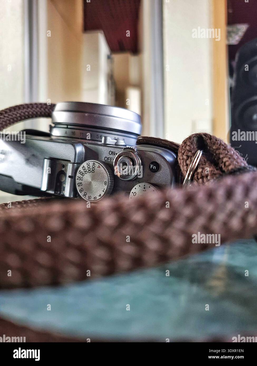 Vecchia telecamera dall'atmosfera nostalgica. Dispositivo fotografico classico con cinturino in pelle e messa a fuoco morbida Foto Stock