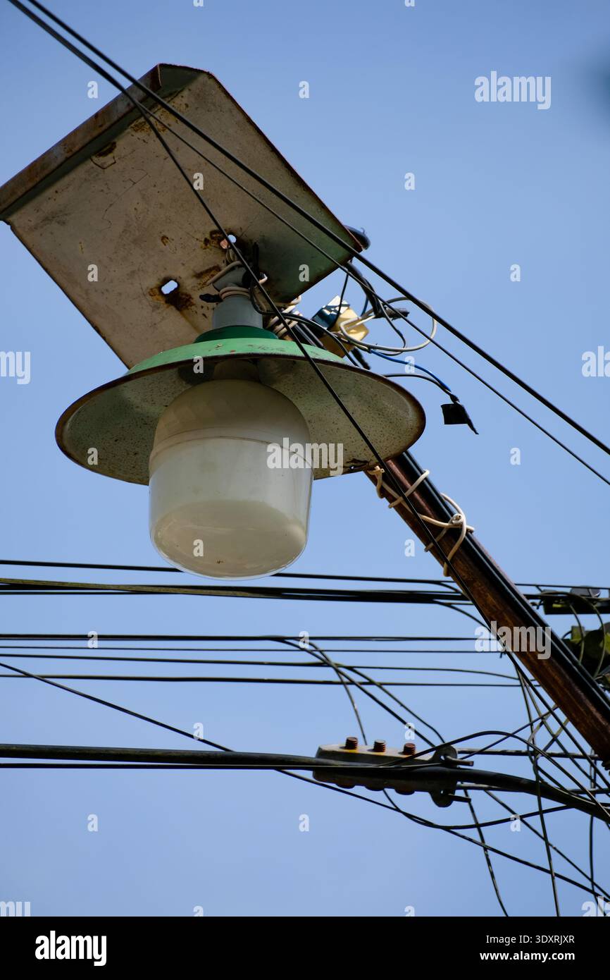 Lampada da strada e cavo elettrico disordinato contro il cielo azzurro Foto Stock