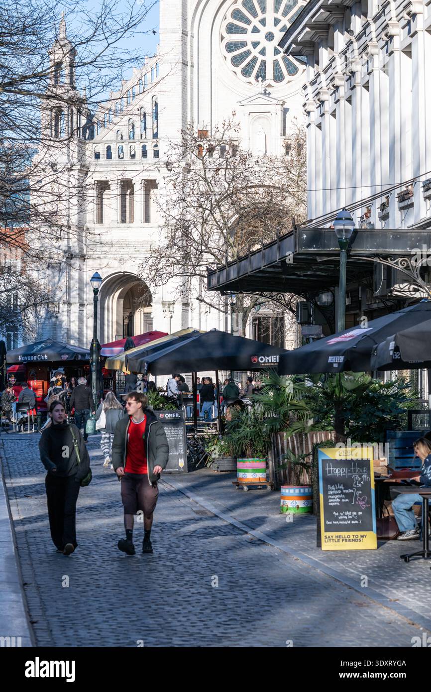 Vivace Oude Graanmarkt e Sint-Katelijneplein con caffetterie e terrazze piene di gente che gode del primo sole primaverile vicino a Sint-Katelijnekerk i. Foto Stock