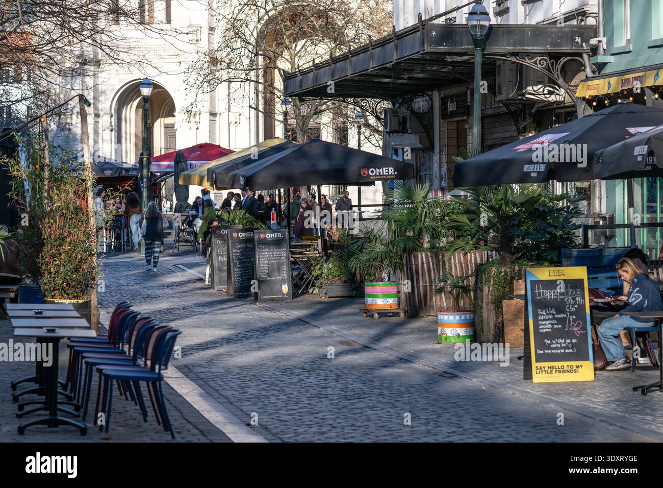 Vivace Oude Graanmarkt e Sint-Katelijneplein con caffetterie e terrazze piene di gente che gode del primo sole primaverile vicino a Sint-Katelijnekerk i. Foto Stock