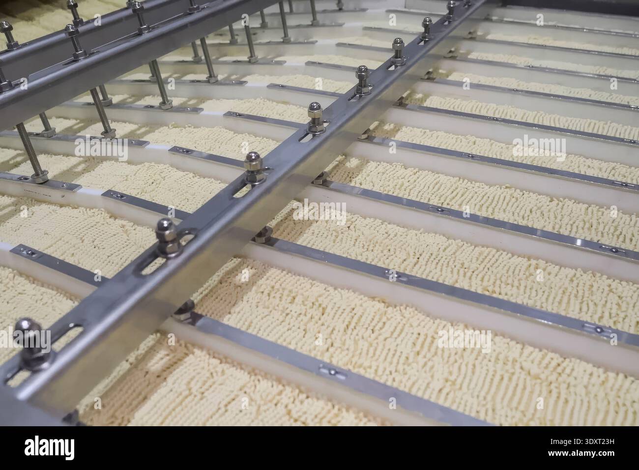 Linea di produzione istantanea di spaghetti. porzioni di spaghetti sul trasportatore, industria alimentare di massa. Foto Stock