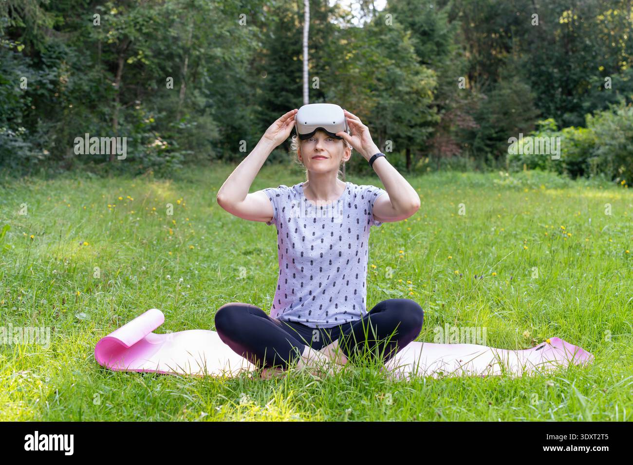 Una donna adatta gli occhiali VR, preparandosi a un'esperienza educativa immersiva in natura. Questa immagine rappresenta il futuro dell'apprendimento Foto Stock