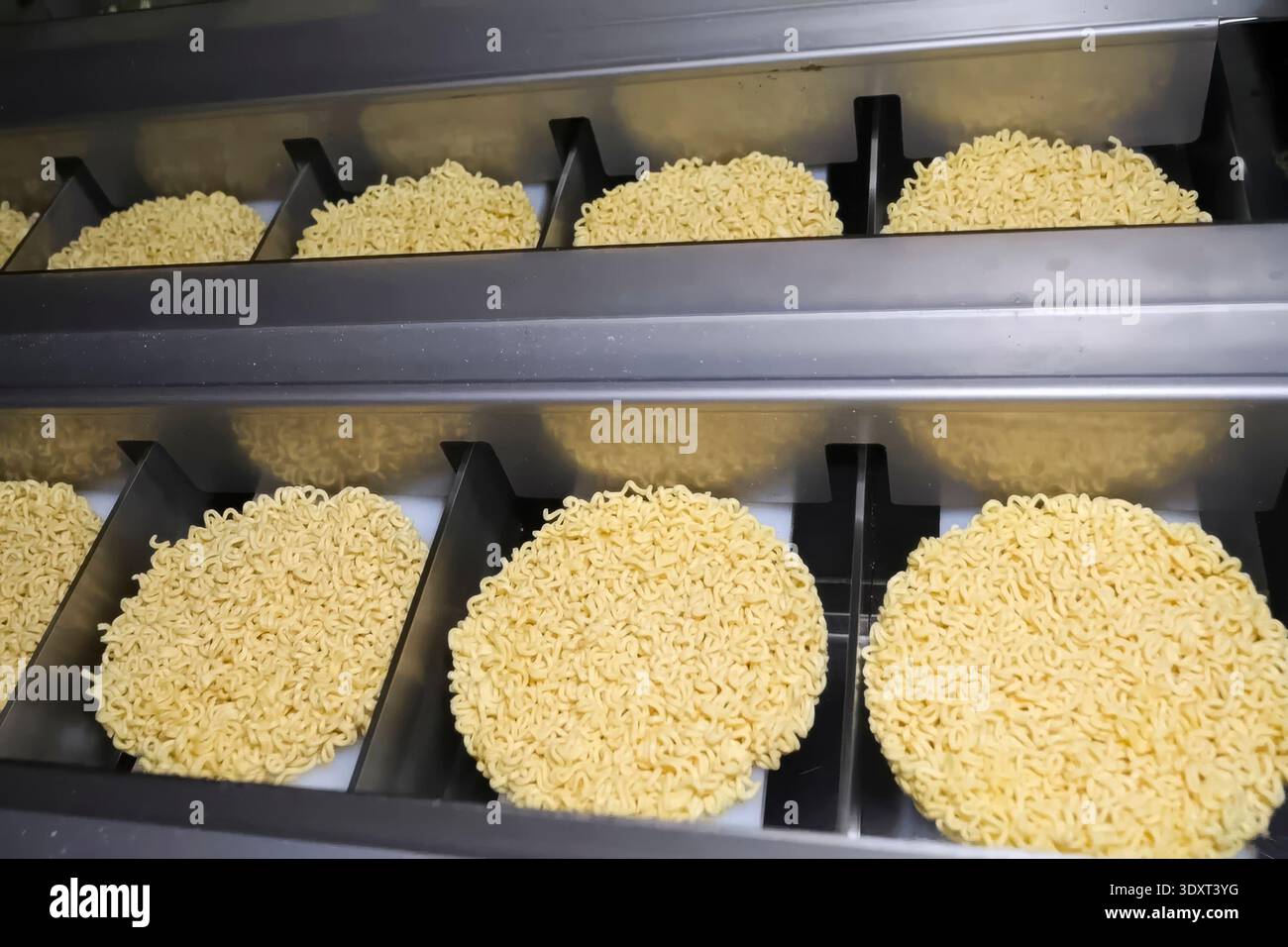 Linea di produzione istantanea di spaghetti. porzioni di spaghetti sul trasportatore, industria alimentare di massa. Foto Stock