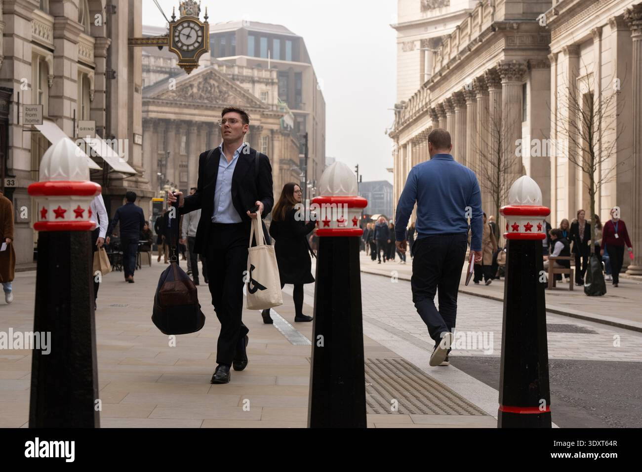 La gente passa davanti al Royal Exchange di Londra. L'iconica torre dell'orologio è visibile. Foto Stock