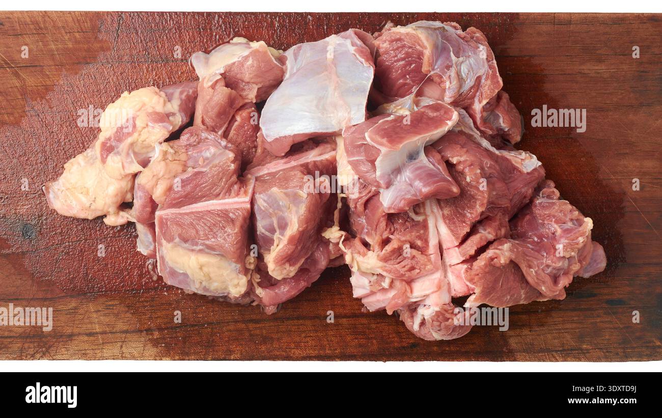 pezzi di manzo crudi tritati su tagliere di legno marrone, consistenza di carne rossa umida con grasso visibile e fibre muscolari, vista dall'alto in primo piano, cucina Foto Stock
