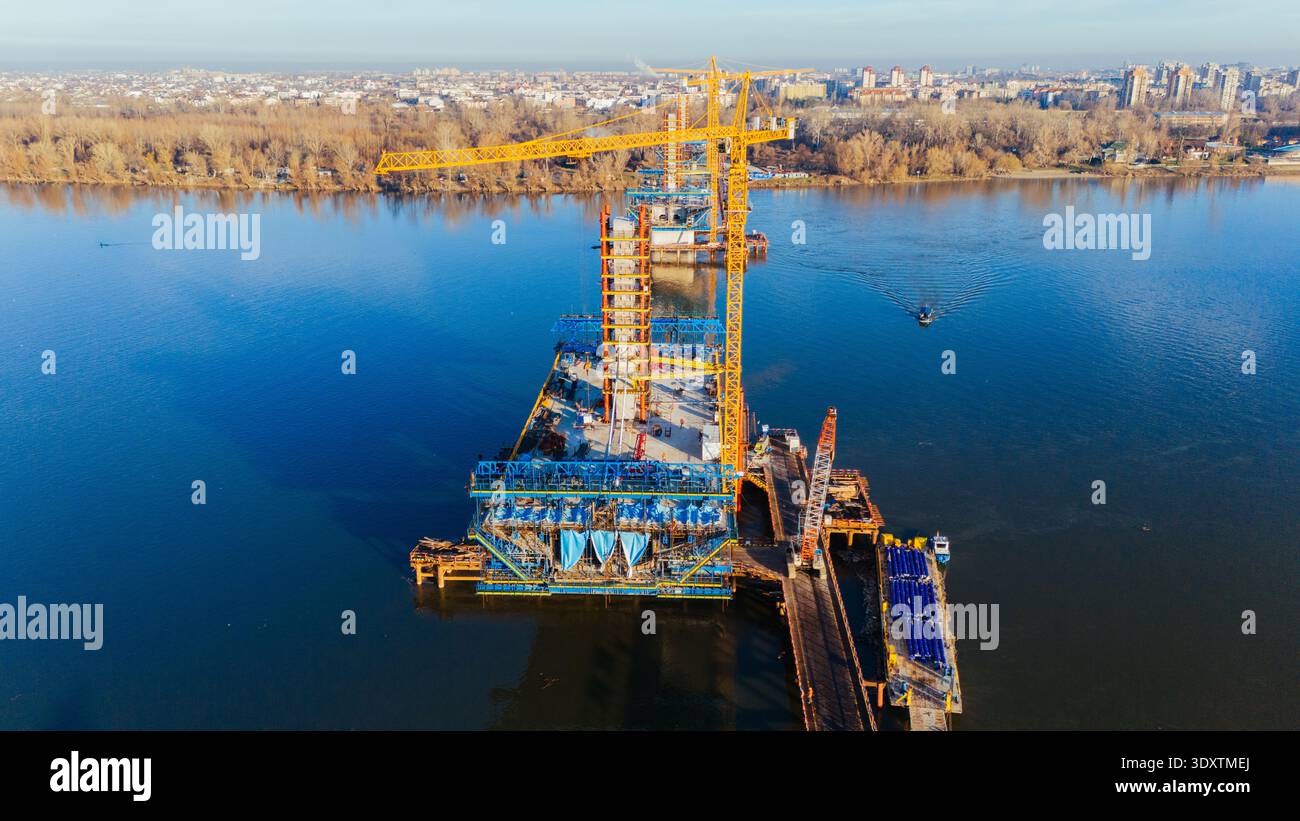 Veduta aerea di un vivace cantiere sull'acqua con una gru torreggiante e la struttura in via di sviluppo, Novi Sad, Vojvodina, Serbia. Foto Stock