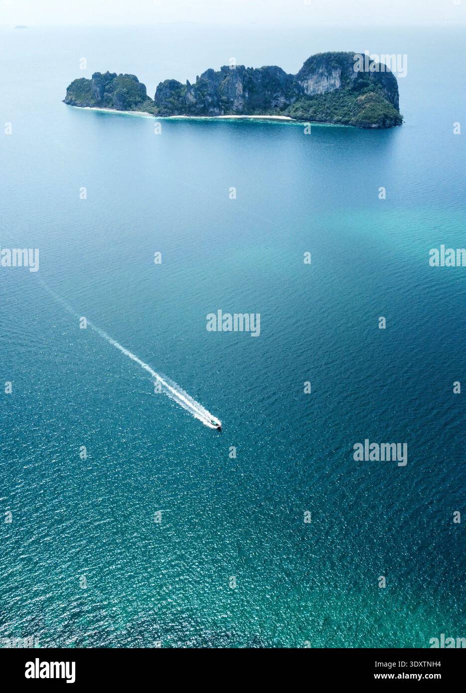 Vista aerea di una barca che affetta le acque turchesi verso la lontana e aspra isola, Khao Lak, Phang Nga, Thailandia. Foto Stock