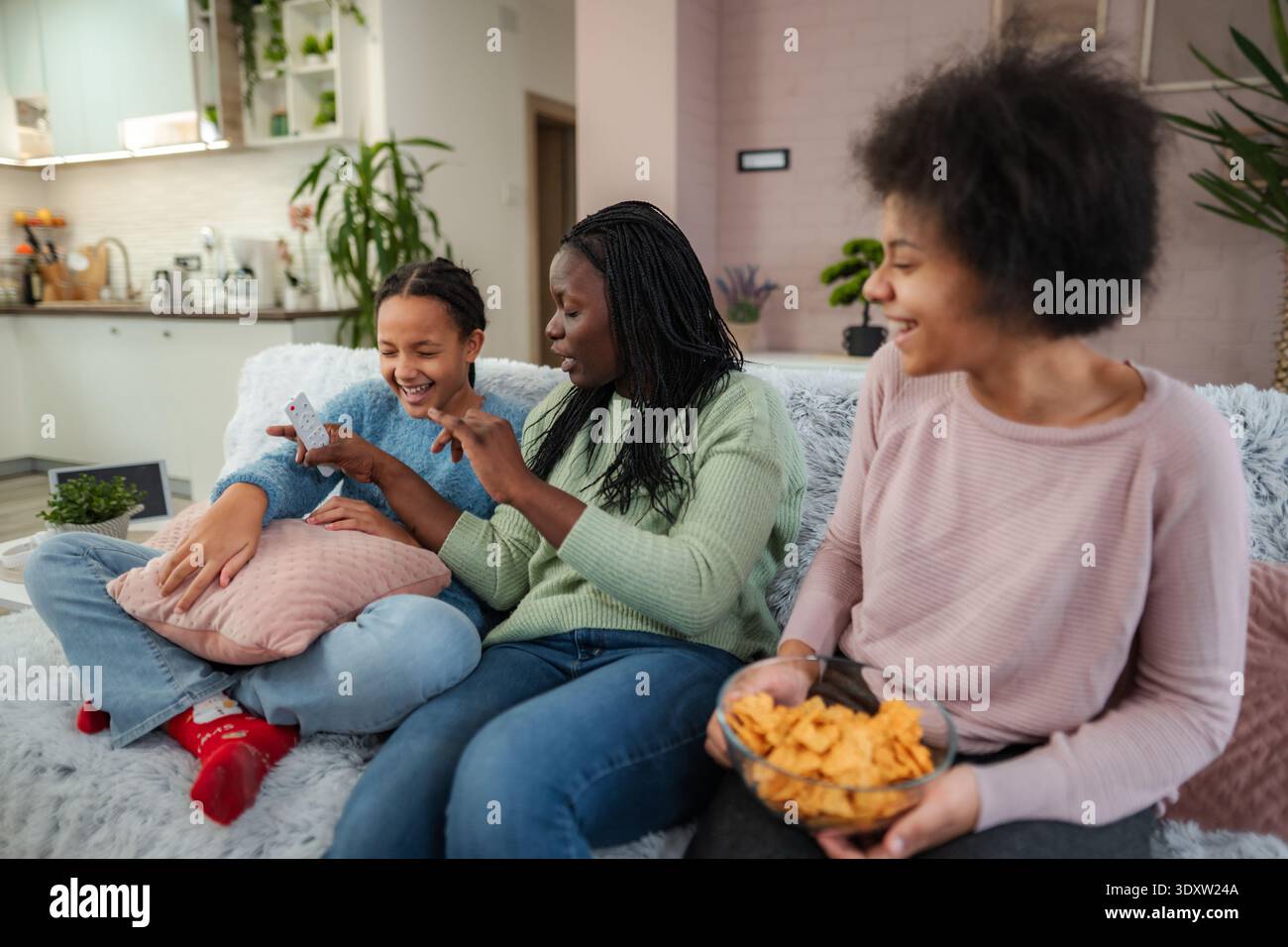 Gli amici trascorrono un pomeriggio accogliente insieme, ridendo e condividendo storie in un caldo soggiorno pieno di piante e comfort Foto Stock