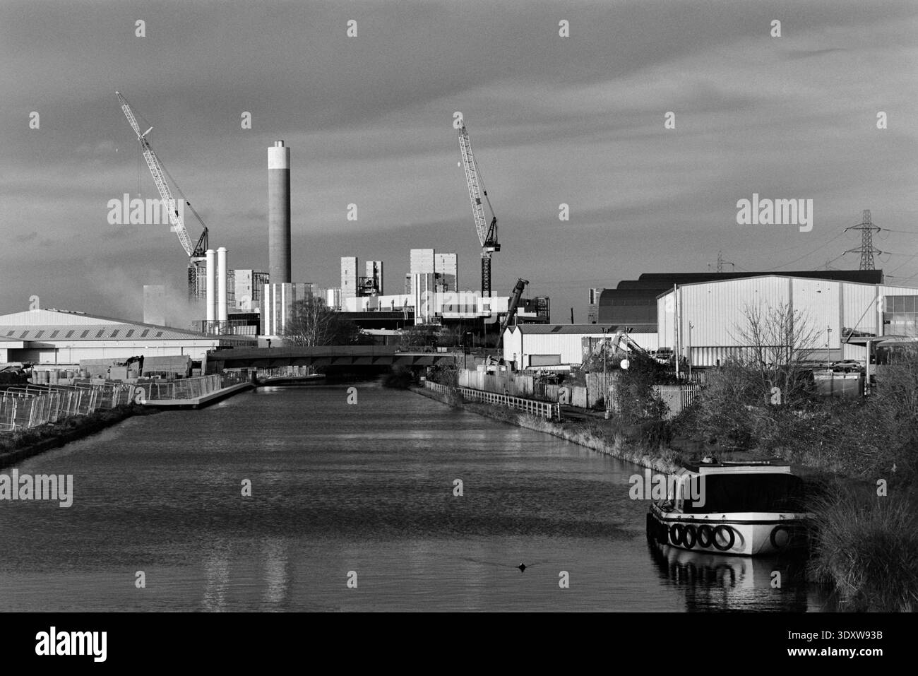 La navigazione sul fiume Lea a Edmonton, North London, Regno Unito, in inverno, guardando verso edifici industriali e gru Foto Stock