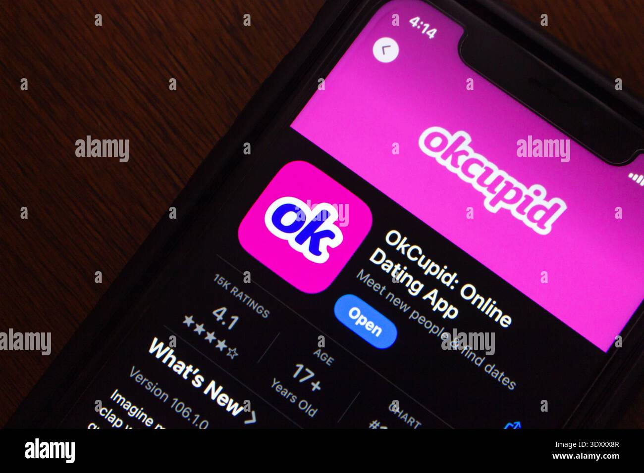 Quito, ECUADOR - 13 ottobre 2025 : smartphone che visualizza la pagina dell'app OkCupid con logo, valutazione e opzione di download, posizionato su una superficie di legno scuro. Foto Stock