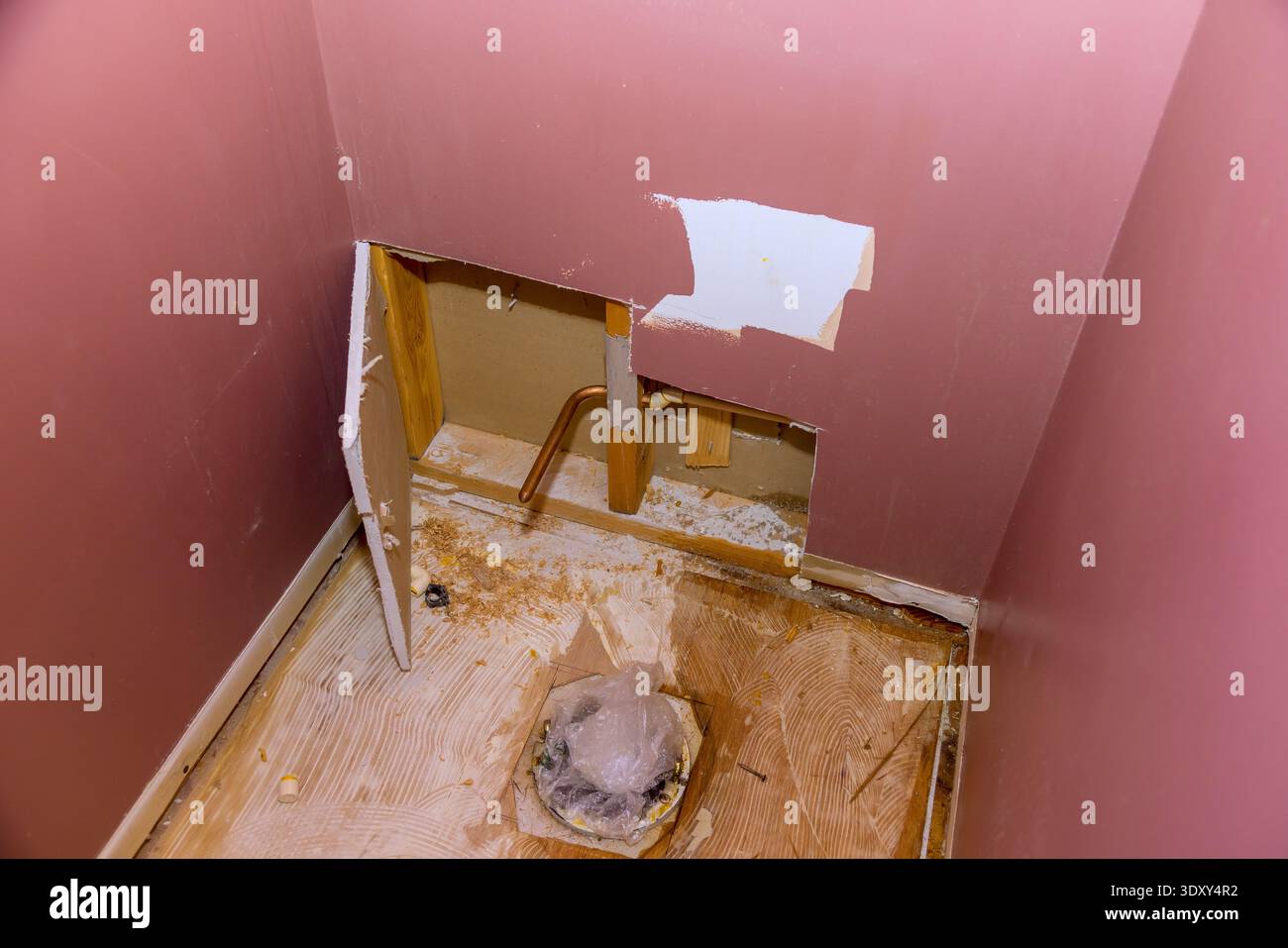 Il muro è tagliato in posizione aperta esponendo i tubi idraulici per la riparazione del bagno che avviene in casa. Foto Stock