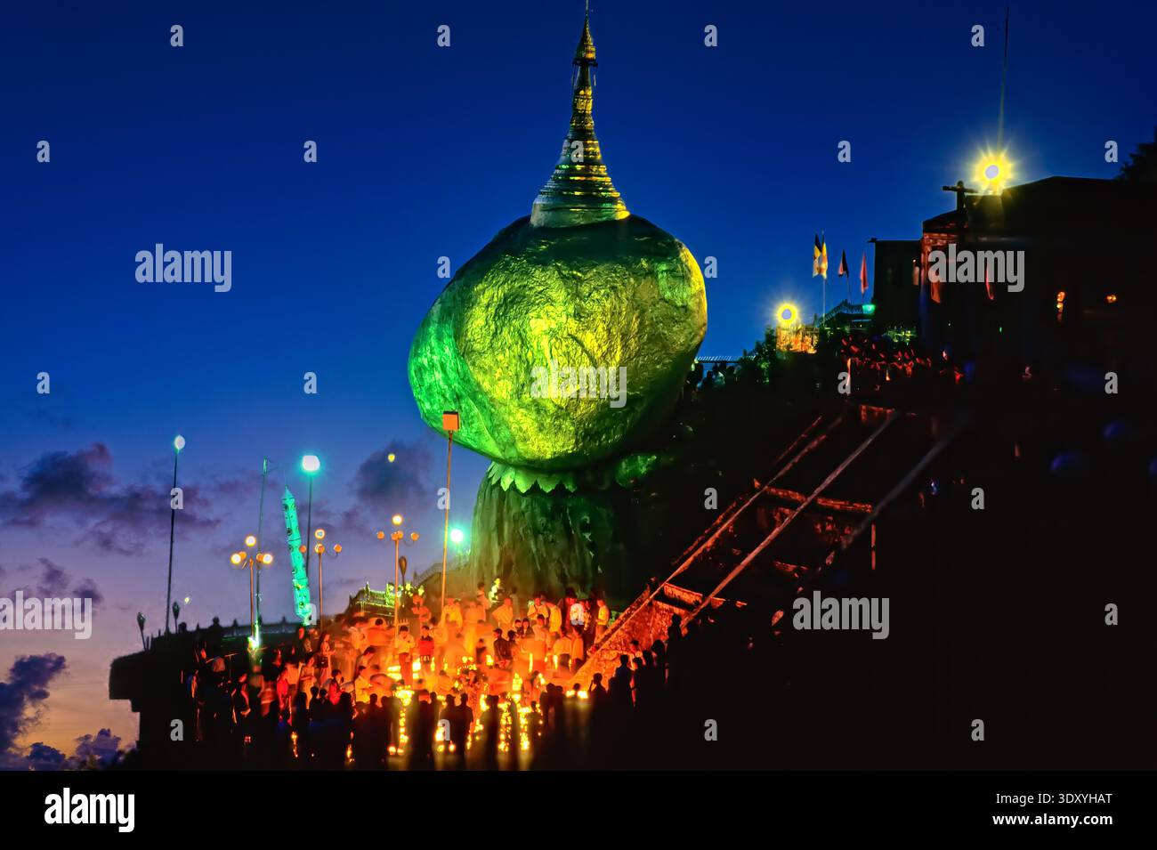 I turisti si radunano intorno alla Pagoda di Kyaiktiyo e alla Golden Rock in Myanmar al calare della notte. Le luci illuminano l'area, creando una scena vivace. Foto Stock