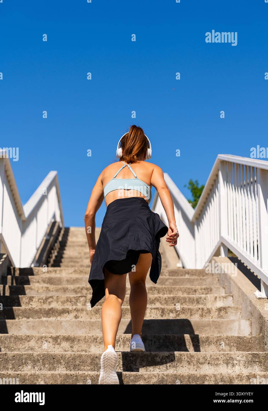 Vista posteriore della donna attiva che sale le scale in città. Foto Stock