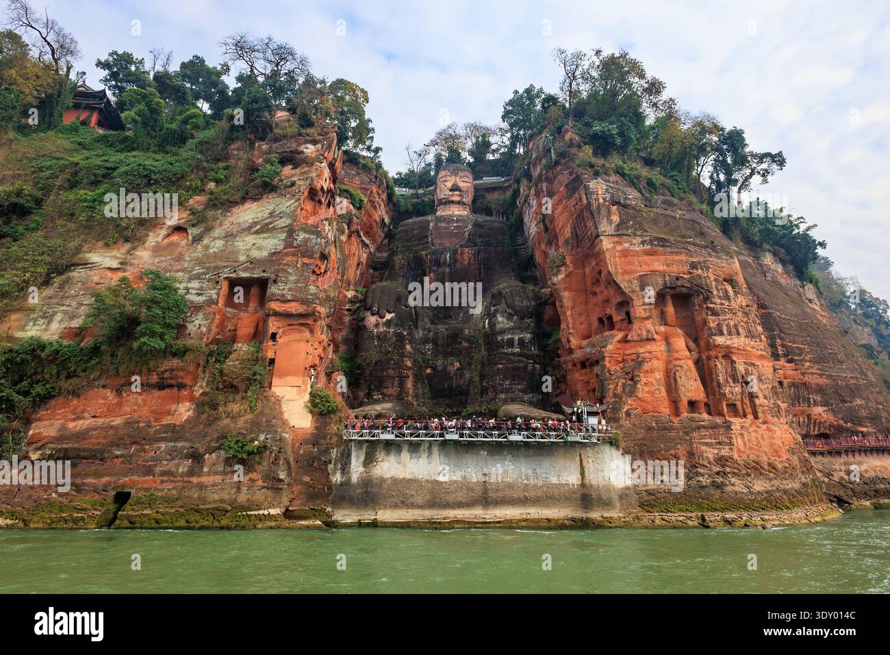 il gigante buddha di Leshan seduto sulla parete della scogliera con la vista dei turisti dalla piattaforma lungo il fiume dadu Foto Stock