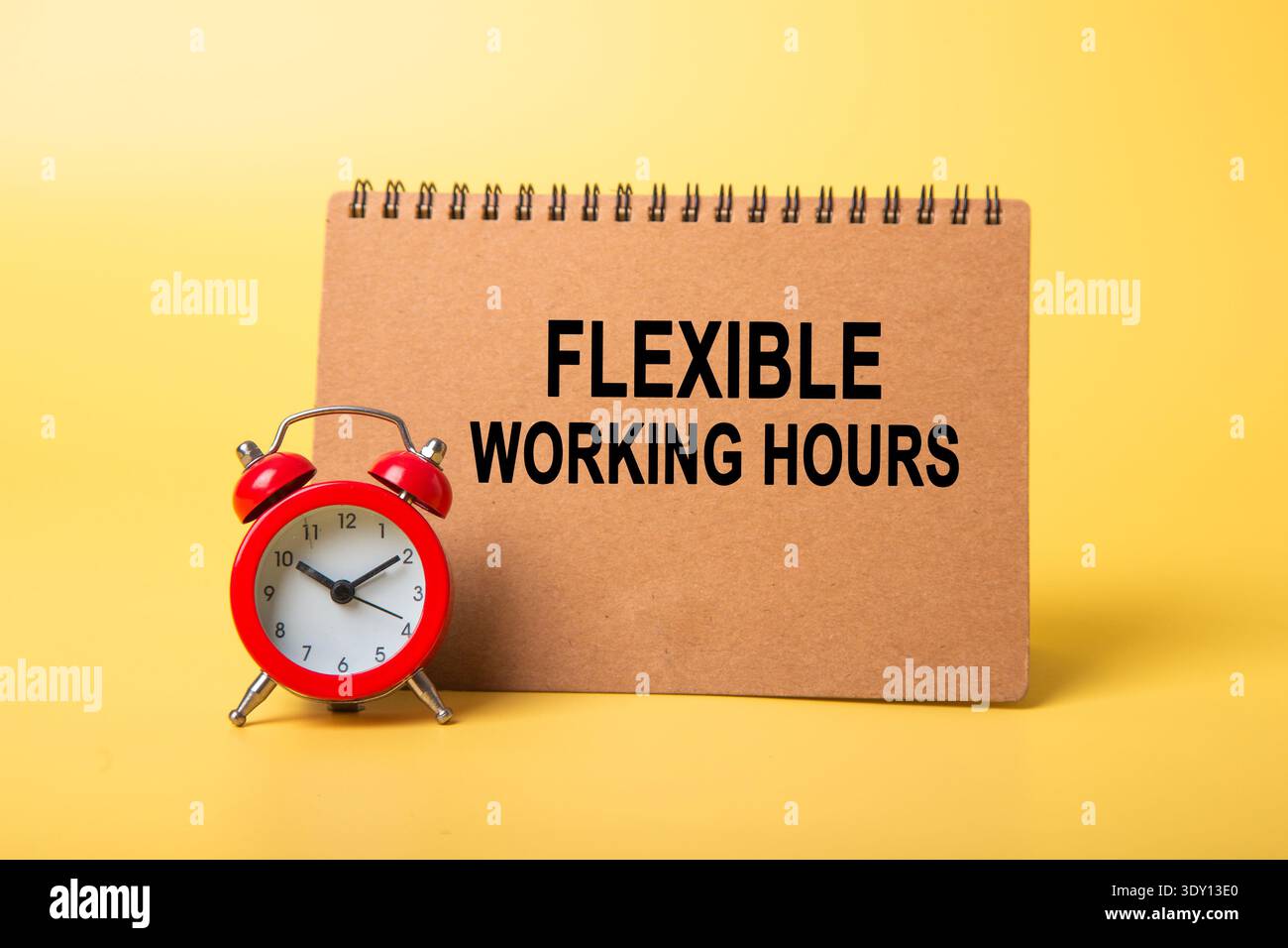 Blocco note che visualizza orari di lavoro flessibili con sveglia rossa su sfondo giallo Foto Stock