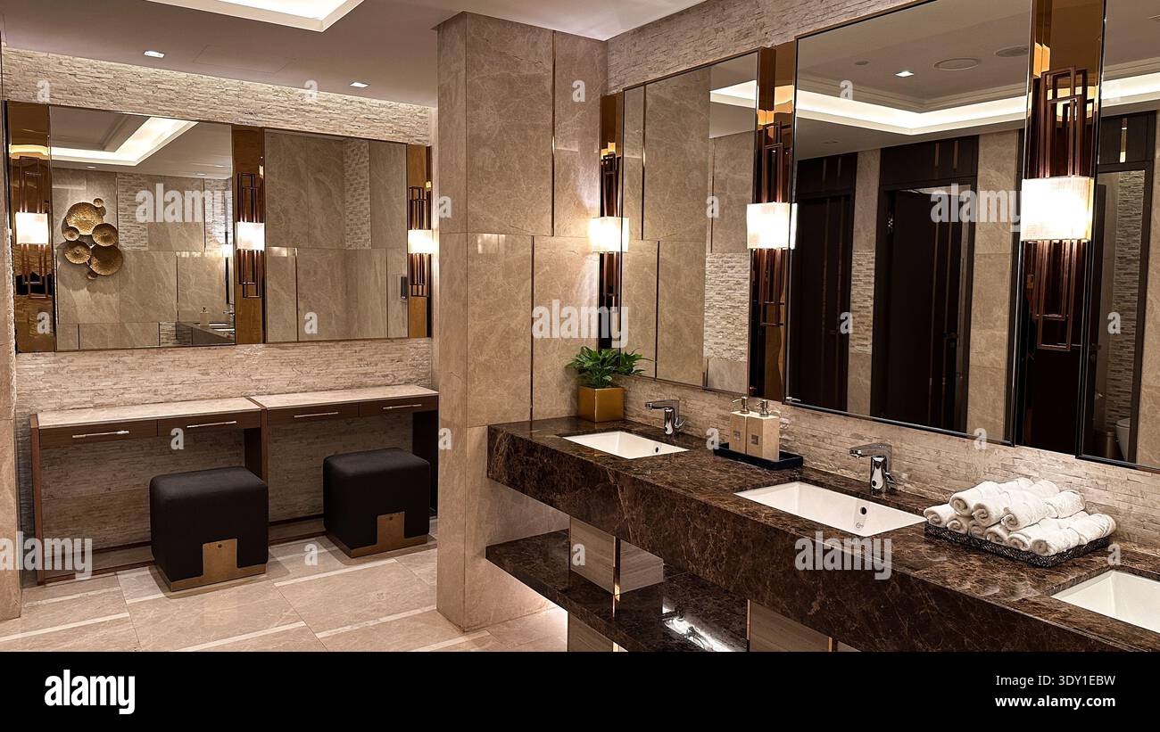 Eleganti interni del bagno dall'atmosfera lussuosa, con uno splendido doppio lavabo in marmo, specchi a parete e sofisticate lampade. Foto Stock
