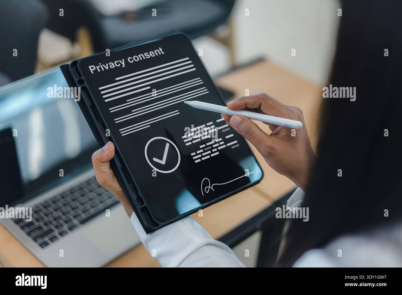 Primo piano di una donna d'affari che utilizza una penna stilo per firmare un modulo di consenso digitale sulla privacy su uno schermo di un tablet, garantendo la protezione dei dati e la conformità legale Foto Stock