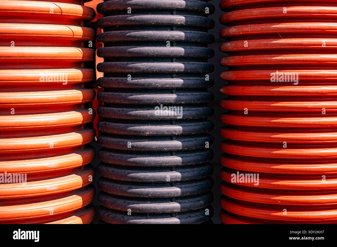 Tubi corrugati arancioni e neri che formano uno sfondo industriale con nervature Foto Stock
