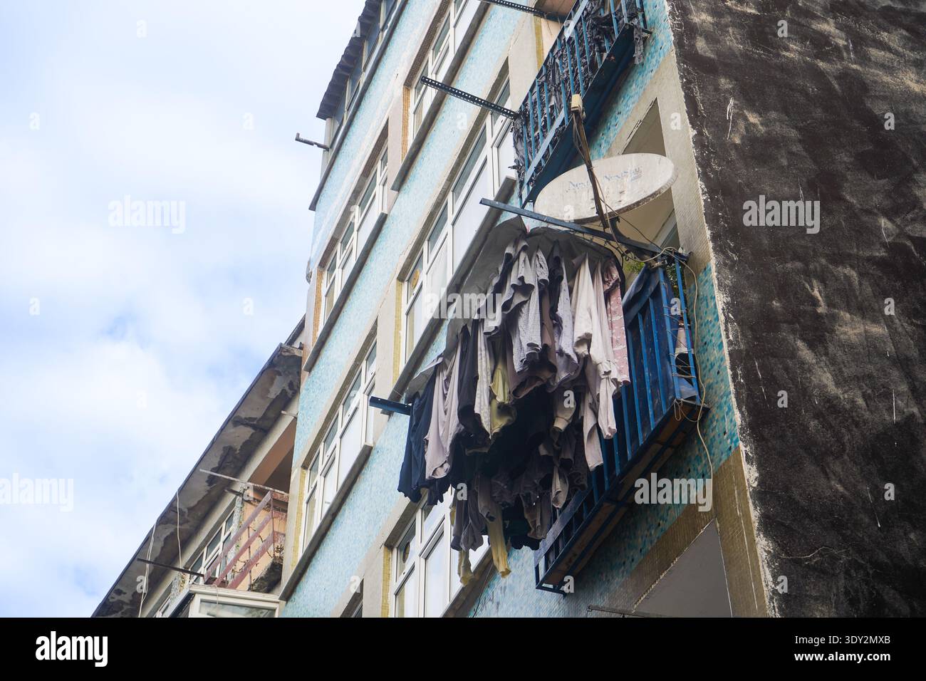 Lavanderia appesa su un balcone con piastrelle blu, che mostra le abitudini locali e la consistenza urbana. Foto Stock