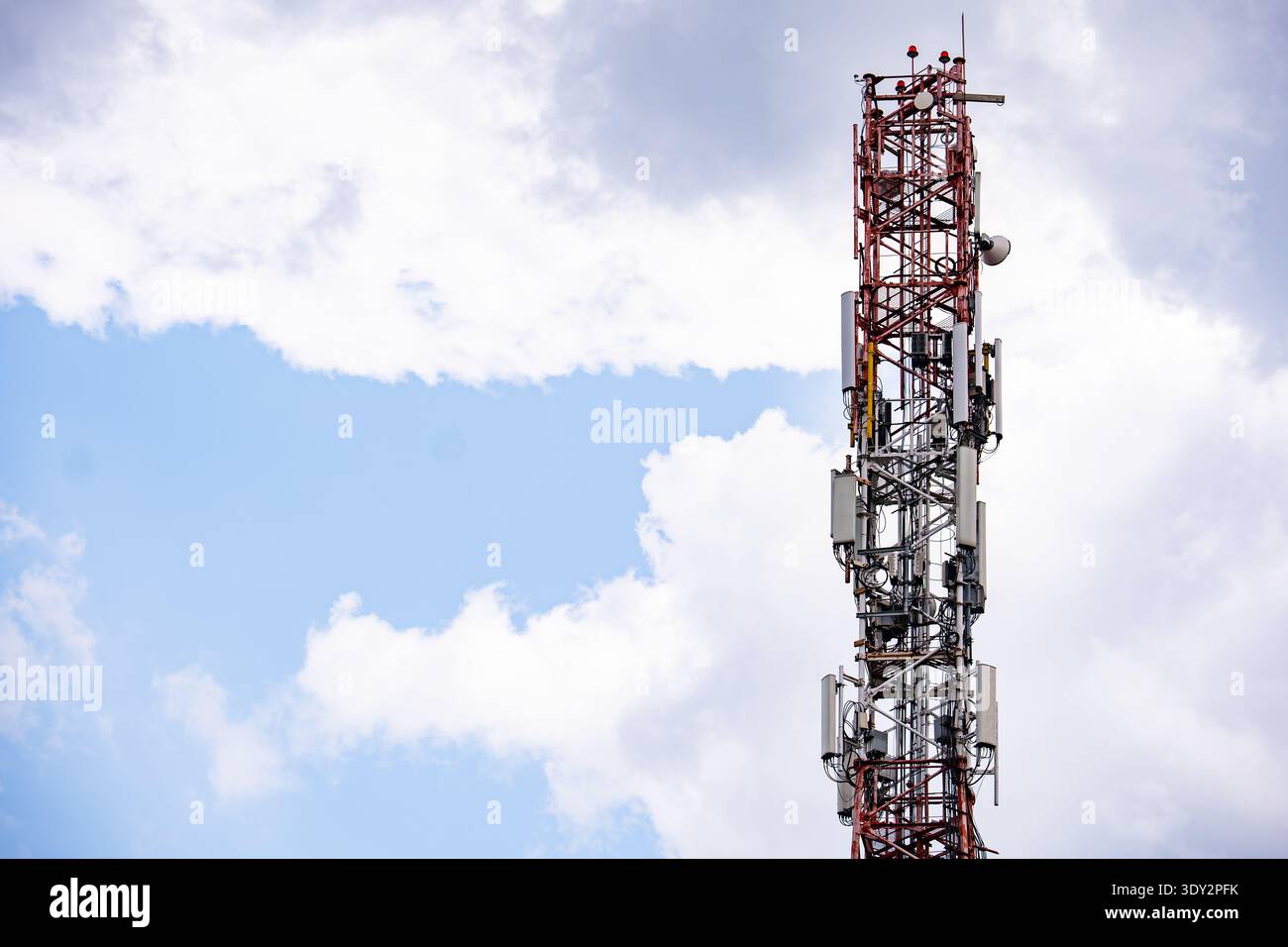 Torre di telecomunicazione che fornisce copertura del segnale cellulare e mobile contro un cielo nuvoloso Foto Stock