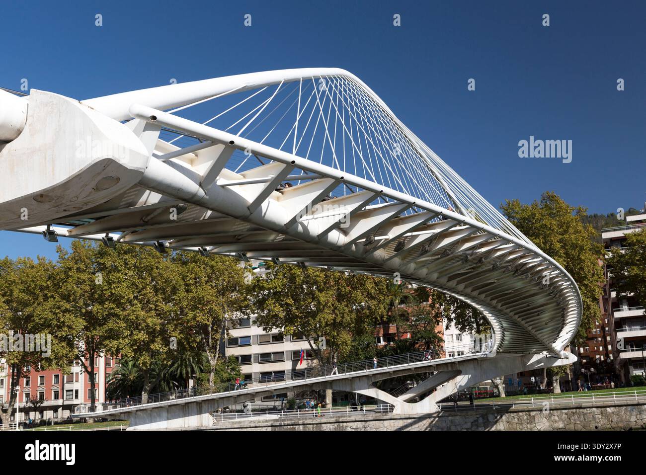 Vista ad angolo basso del bianco e curvo Ponte Zubizuri progettato da Santiago Calatrava a Bilbao, Spagna, sotto un cielo azzurro. Foto Stock