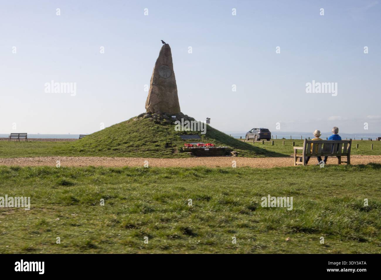 Una coppia di anziani siede in una tranquilla riflessione su una panchina commemorativa, guardando verso il Solent dal COPP Heroes Memorial sull'isola di Hayling Foto Stock